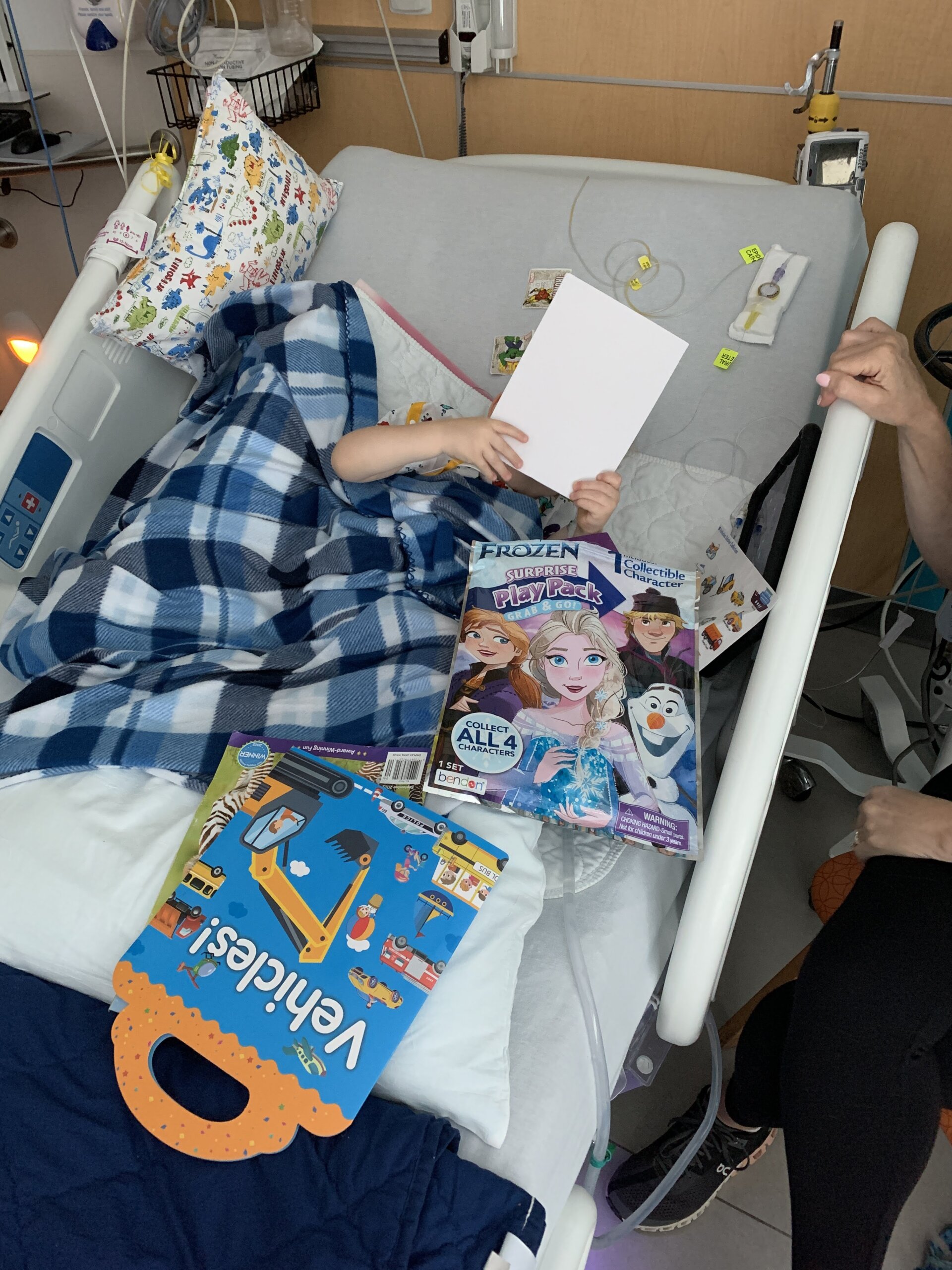 Boy laying in hospital bed with toy, etc around him